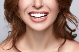 woman with perfect porcelain veneers showing off her teeth